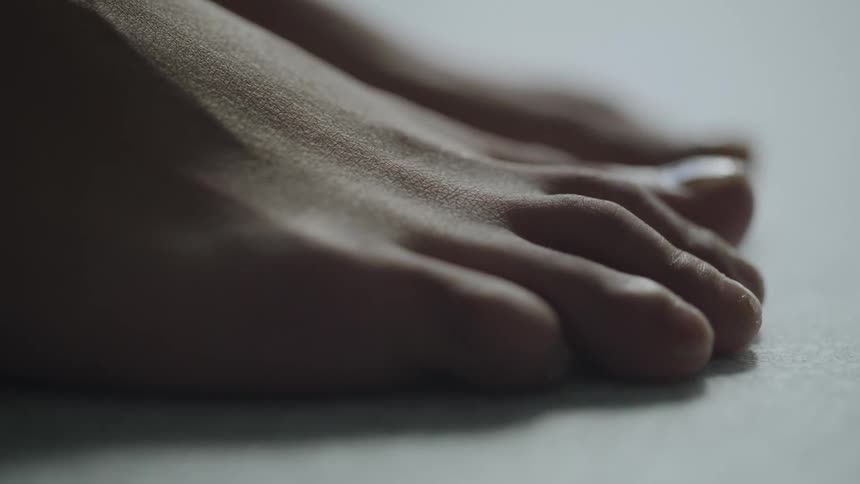 A woman places her right foot on the ground next to her left foot