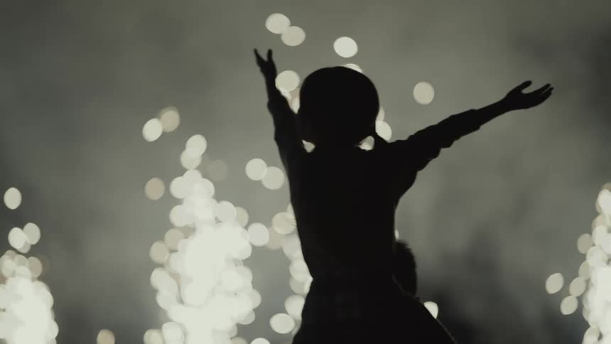 Silhouette of a family celebrating in front of a fireworks display at night