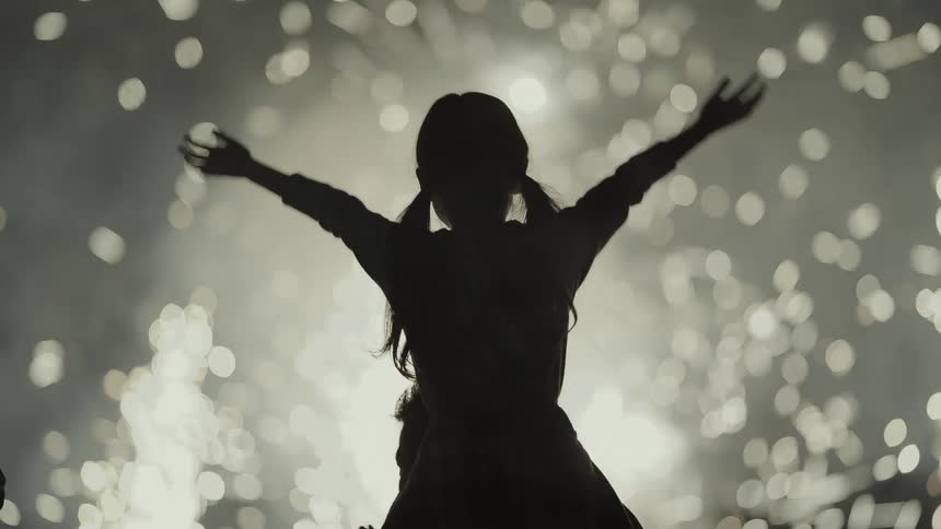 Silhouette of a girl in front of a fireworks display at night