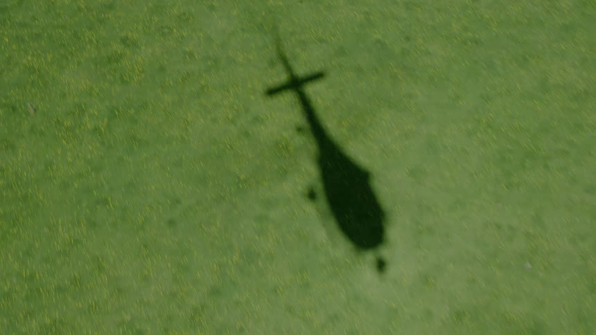A helicopters shadow is showing on the grass