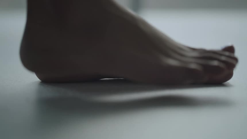 Woman places her bare feets over a white floor