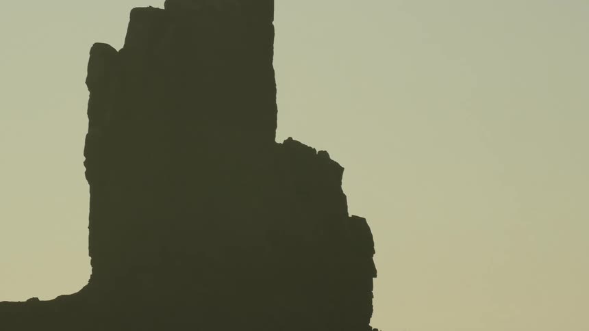 A desert landscape with a cliff the sky and clouds in the background