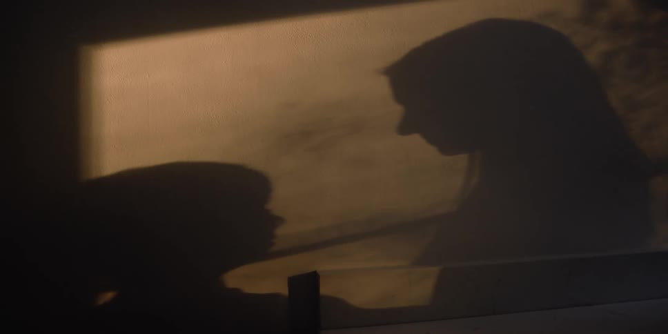 Shadow silhouette of a woman kissing the forehead of a boy