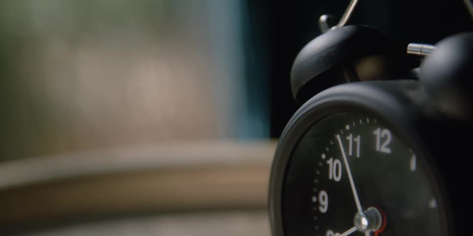 Close up of a vintage black analog alarm clock over a table
