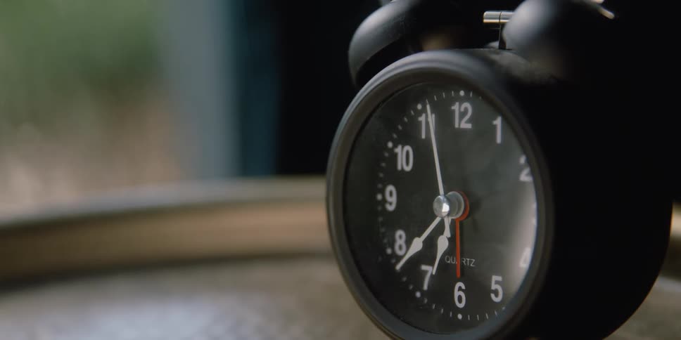 Second hand moves around face of alarm clock sitting on flat surface