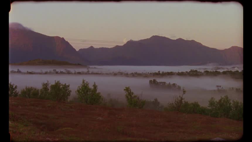 A film of fog covering the land in front of a mountain range