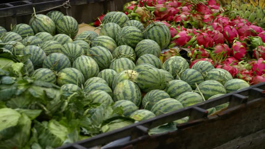 A long row of produce and fruit baskets contain various items for sale at a market
