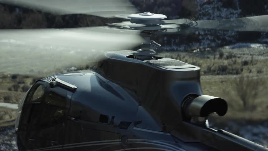 Aerial drone footage of a helicopter hovering over a valley and river during the daytime