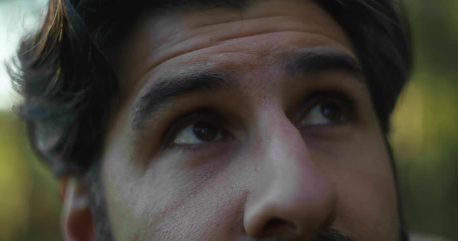 A man looks sideways at a distance as he is standing outdoors