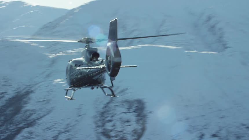 A helicopter flying over a snow covered mountain