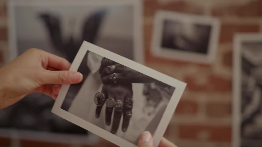 A woman removes a photograph from a brick wall display and looks at it