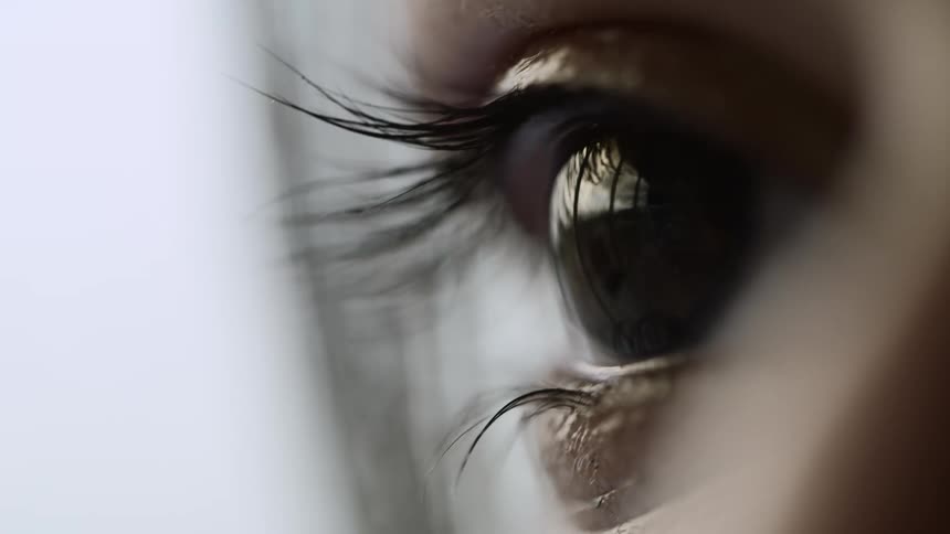 A person eye blinking in a room with a wall in the background