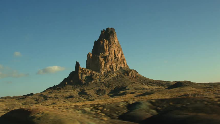 A desert landscape with hills and peaks with the sky and clouds in the background