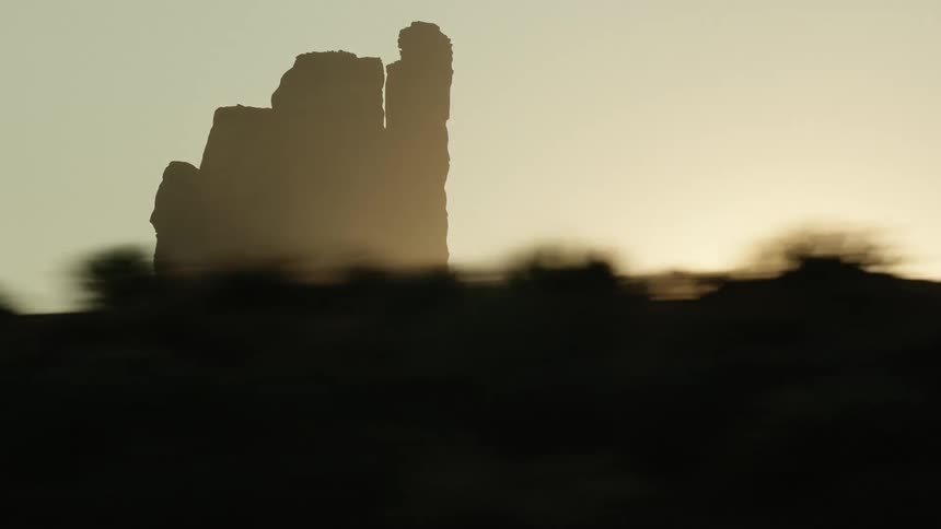 Tall isolated vertical rock formations on a butte in the desert at sunset