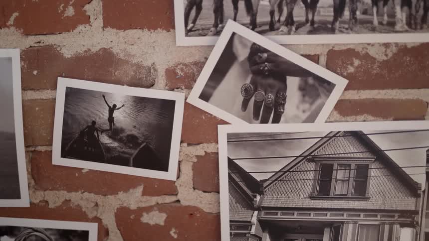 A person lifts a black and white photograph from the wall