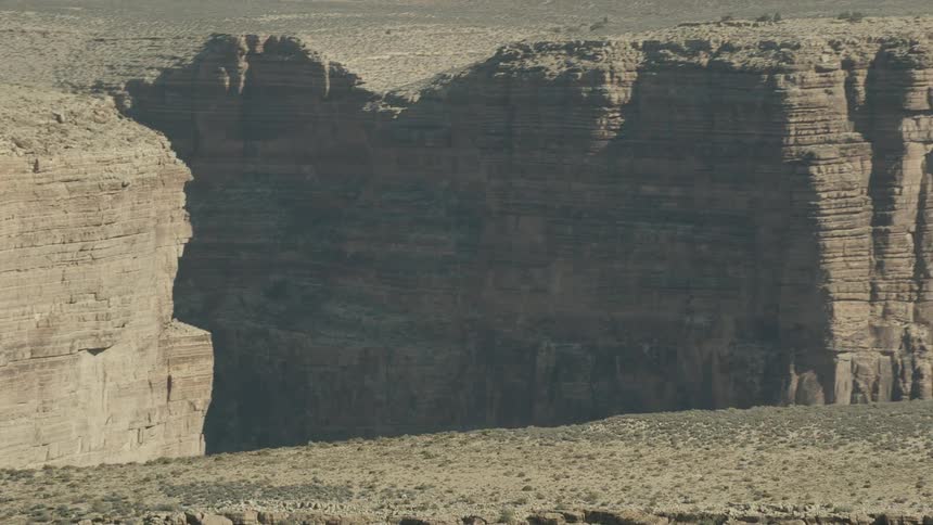 A canyon with shrubs rocks dirt and dust