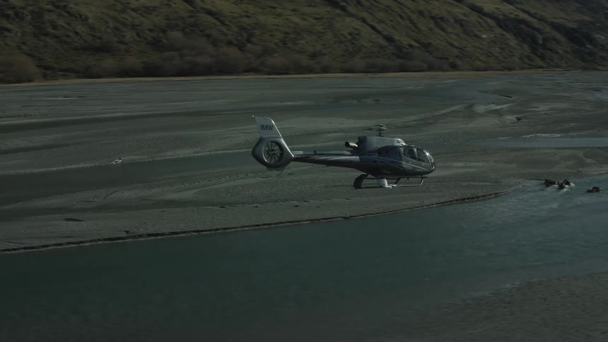 Aerial view of a helicopter flying over a river in the mountains
