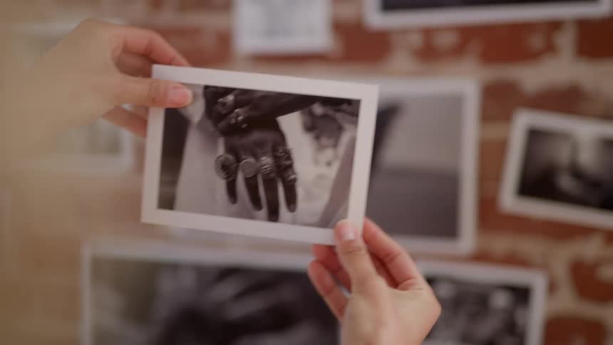 A person in a room looking at a photograph with a wall and a window in the background