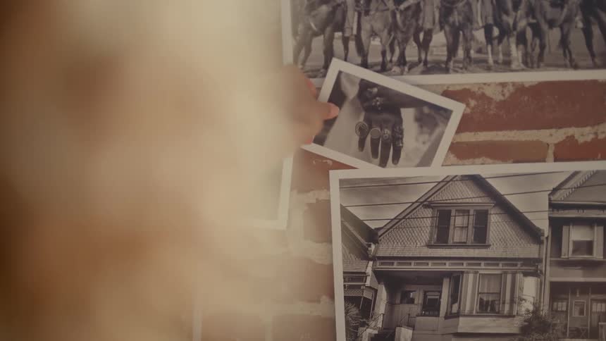 A woman adds another black and white photograph to a display on a brick wall