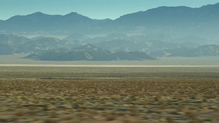 Fog covers mountains and foot hills standing on edge of scrub plains and sand