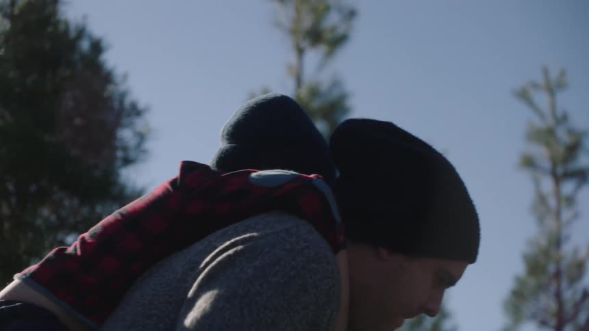 Father carrying son on his back while hiking on a trail in the forest at morning