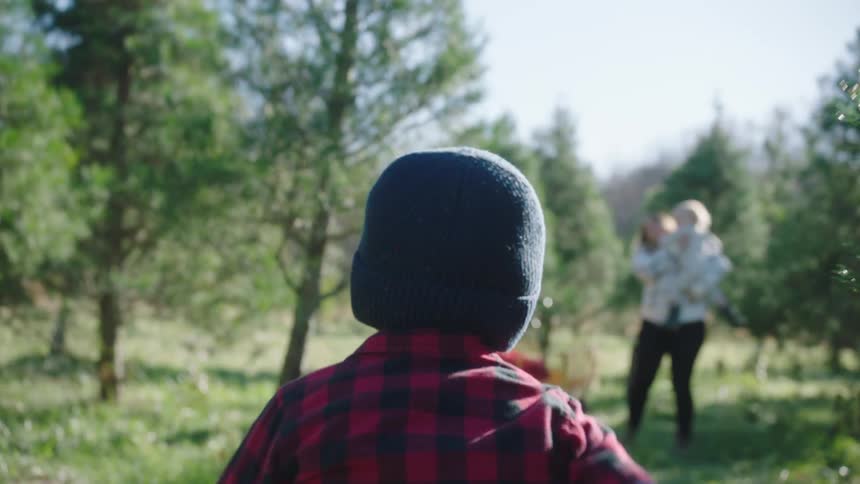 A boy running in an orchard with a man woman and a child in the background