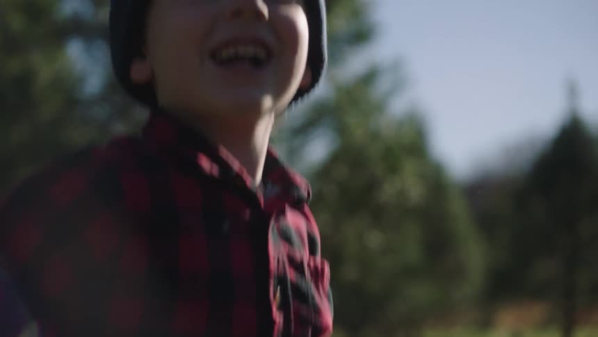 A young boy points out at the distance before turning towards the camera and jumping in excitement