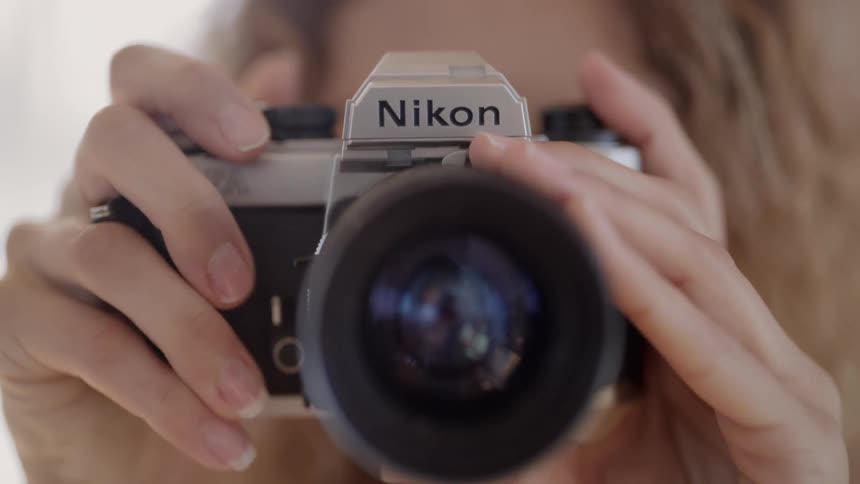 Blonde woman takes pictures with a camera inside a room at home