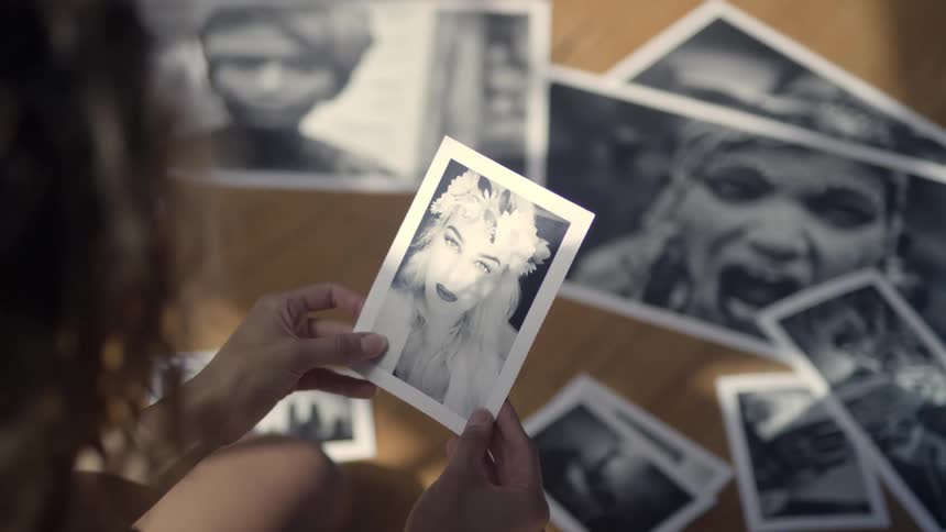 A woman examines photographs while kneeling on the floor