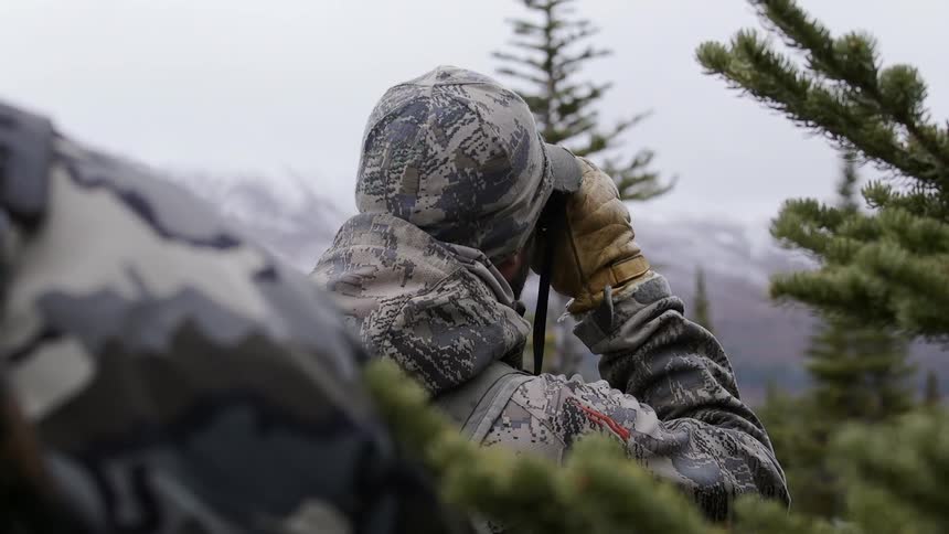 Two people in camouflage standing in the wilderness