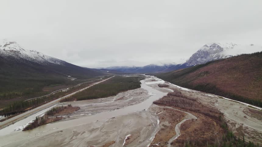 A muddy river basin in a mountain valley on a cloudy day