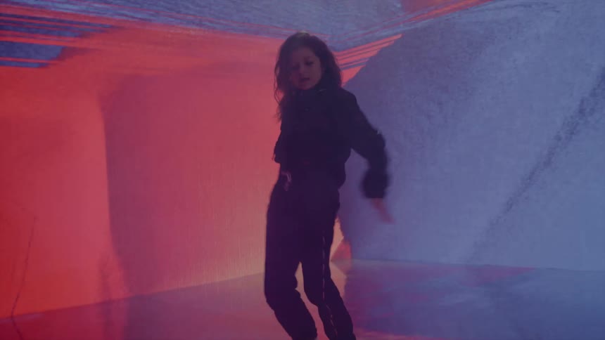 Young woman dances against walls showing different colored patterns