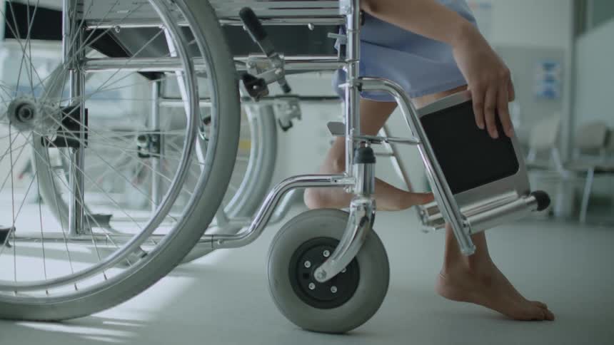 A patient in a hospital adjusts the foot rests on their wheelchair