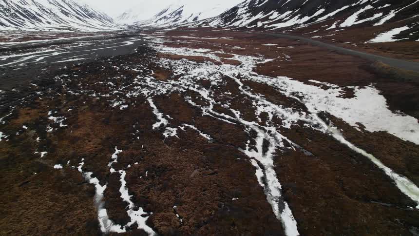 Aerial view of snow and ice traces over the plains between the mountains