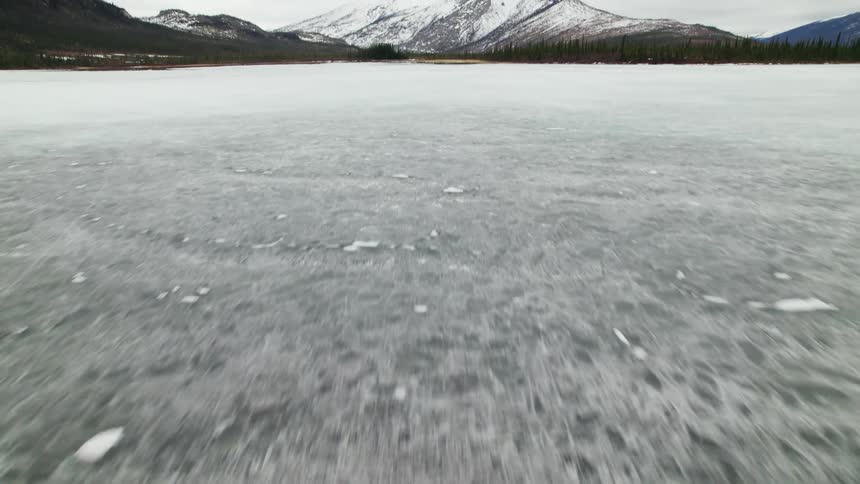 Ice and snow on a lake near the snow covered mountains