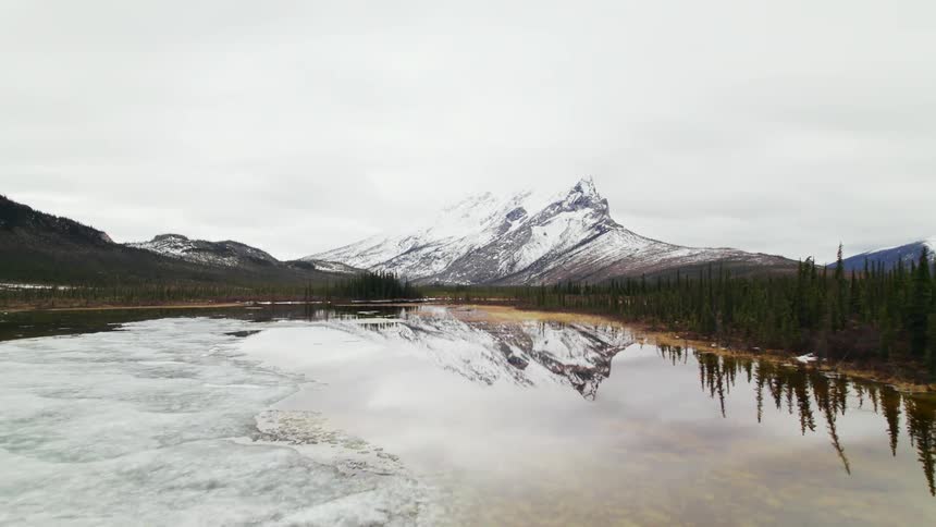 An aerial view of an icy mountain lake on a cloudy winter day