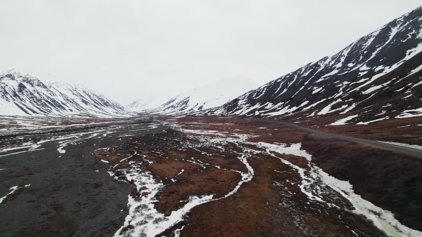 An aerial view of a snowy mountain landscape in winter