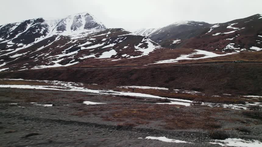 An aerial view of a snowy mountain range on a cloudy winter day