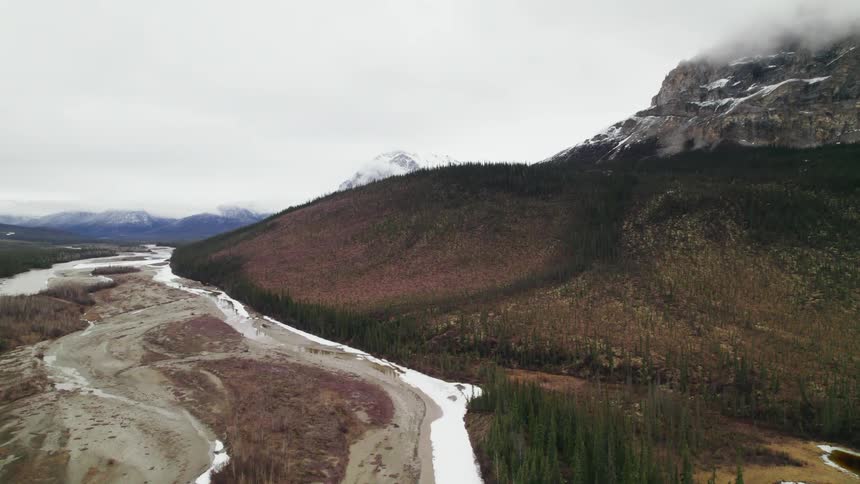 Lake alongside a mountain with light snow covering the top