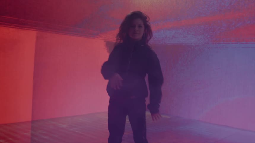 A girl dancing in a room with screens on the wall in the background