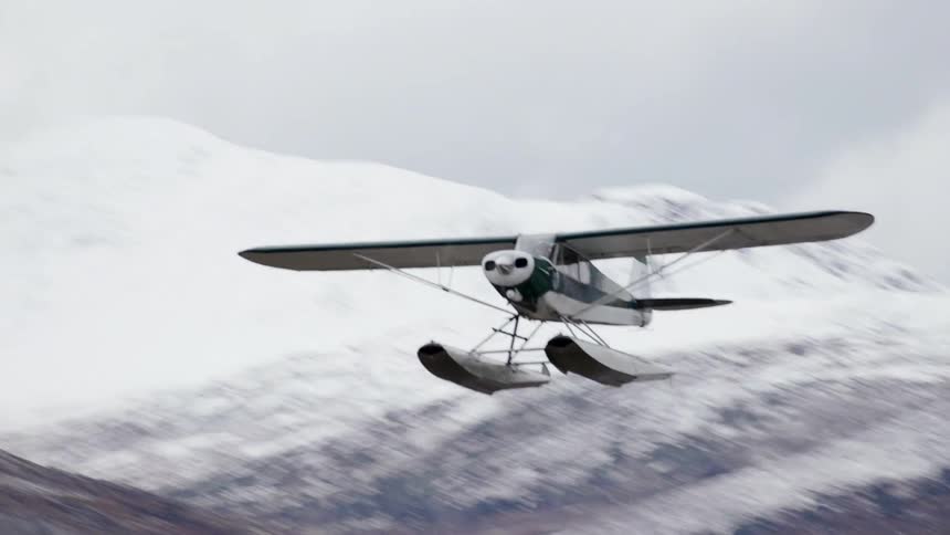A small plane flies over the mountain