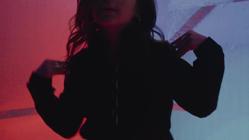 A girl dances hip hop in front of a graphic colorful display