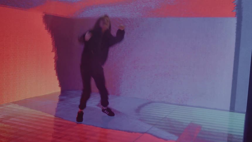 Young teenager dances on stage area composed of digital screens that show various colors and images