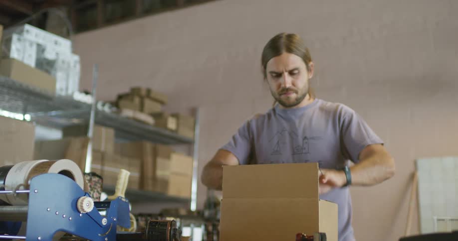 A man in a business prepares a box to ship