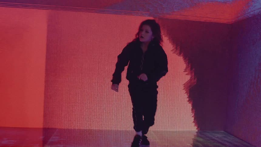 A girl dancing in a room with a screen on the walls in the background