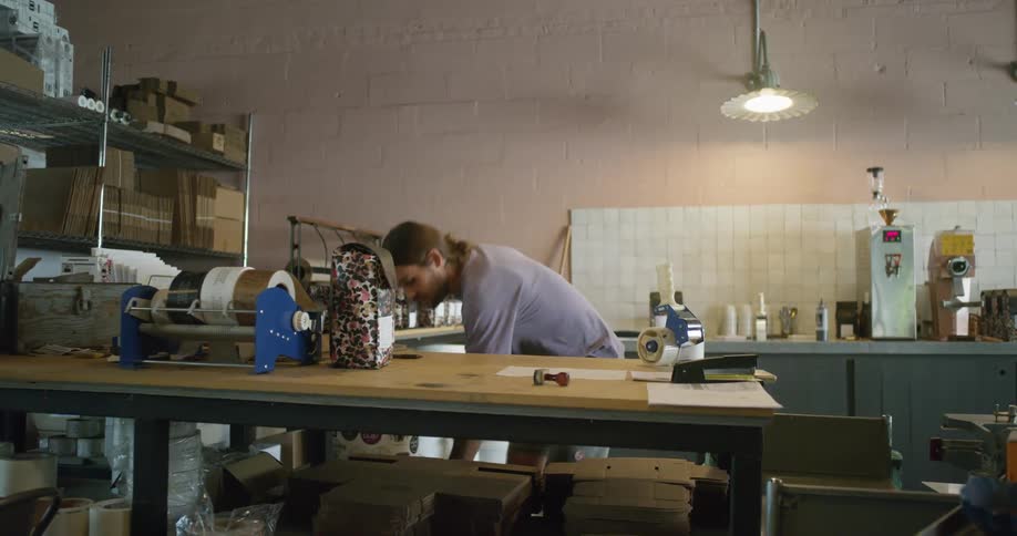 A man uses a package tool on a cardboard box and folds it flat