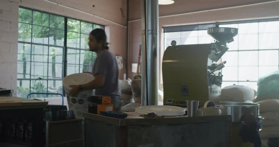 Man in a room with a machine picks up a pail and carries it away