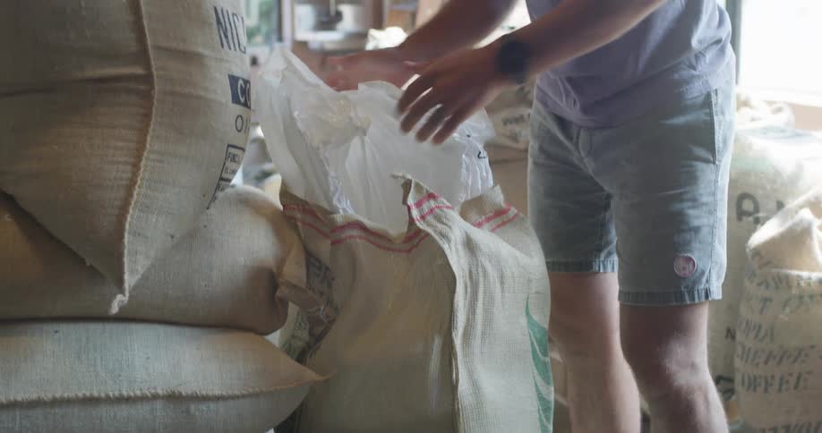 A man puts a sack down and opens the interior bag before grabbing a scoop