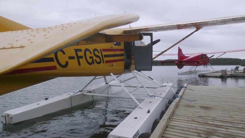 A yellow plane floats near a dock