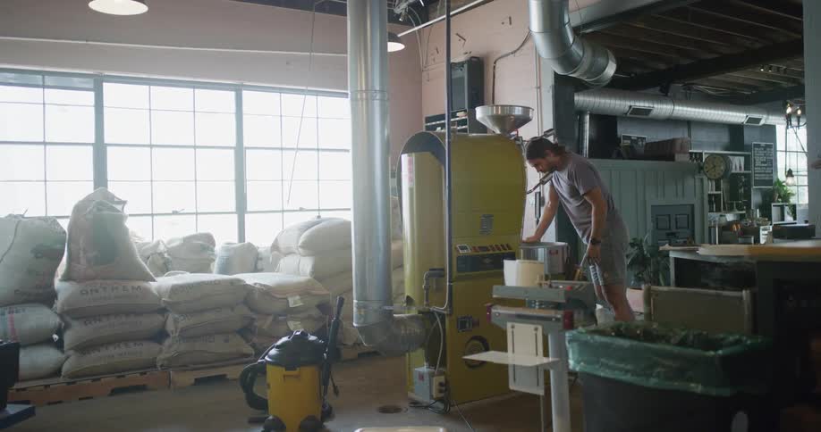 Man leans on a pot and looks inside while standing near a piece of machinery